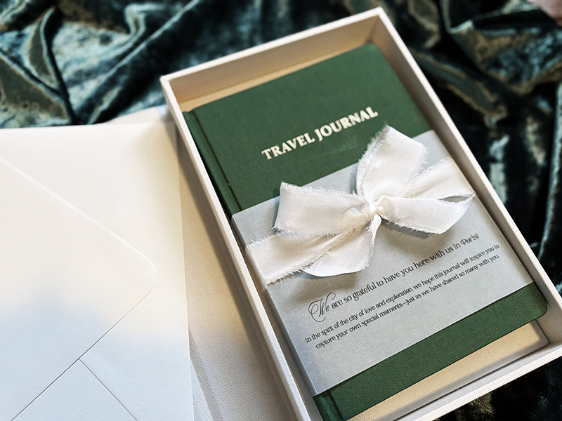 travel journal gift for wedding guests with bow and vellum wrap, wedding invitation gift box ideas, colorado wedding stationery. 2025 wedding stationery inspiration. 2025 wedding stationery trends